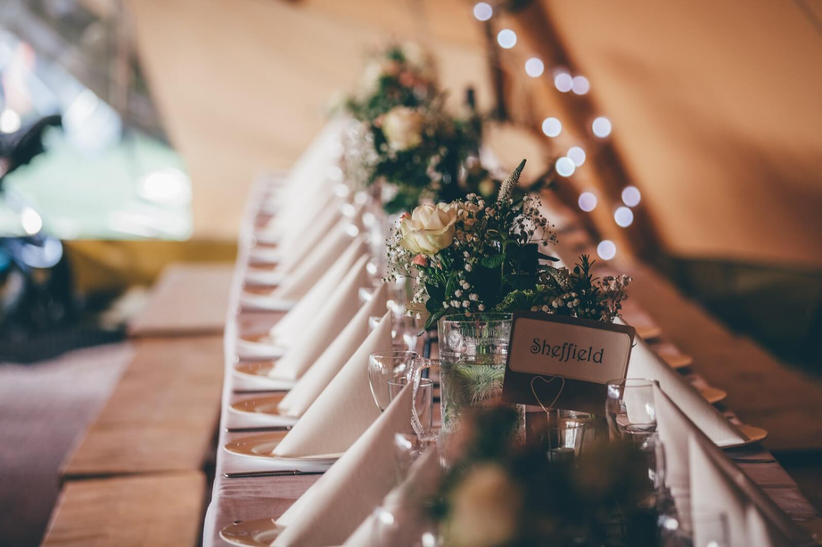 Table jar arrangements inside tipi wedding at Bridge House Barn
